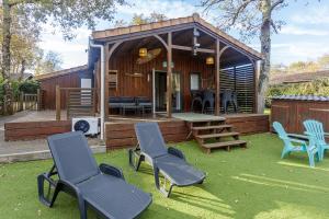 ein Haus mit Stühlen, einem Tisch und einem Grill in der Unterkunft Chalet 809 tout confort en lisière de forêt in La Teste-de-Buch
