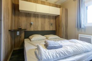 ein Schlafzimmer mit einem Bett mit zwei Kissen darauf in der Unterkunft Chalet 809 tout confort en lisière de forêt in La Teste-de-Buch