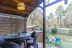 eine abgeschirmte Veranda mit einem Glastisch und Stühlen in der Unterkunft Chalet 809 tout confort en lisière de forêt in La Teste-de-Buch