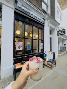 iemand die een drankje vasthoudt voor een winkel bij London Grand in Londen