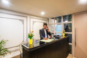 Ein Mann telefoniert an einem Schreibtisch in einem Büro. in der Unterkunft Hotel Travana Stay at Pitampura in Neu-Delhi