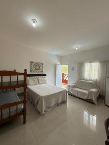 a bedroom with two beds and a couch in it at Pousada na maranduba suites imperio in Ubatuba