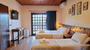 ein Hotelzimmer mit zwei Betten und einem Fernseher in der Unterkunft Hilltop Chalés Gramado in Gramado