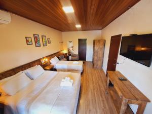 a hotel room with two beds and a flat screen tv at Hilltop Chalés Gramado in Gramado