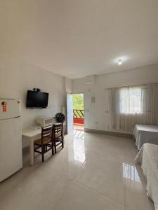 a living room with a refrigerator and a table with chairs at Pousada na maranduba suites imperio in Ubatuba +196 photos