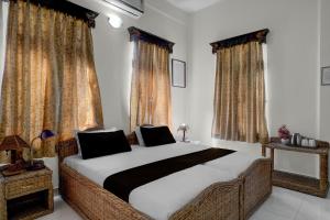 - une chambre avec un grand lit et des rideaux dans l'établissement Hotel O Baruah Bhavan By Axom Inn Heritage, à Guwahati