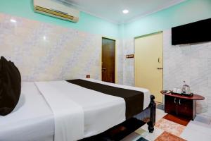 a bedroom with a white bed and a tv at Hotel O Surya Lodge in Guntūr