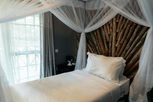 a bedroom with a canopy bed with a window at Kutoka Lodge in Arusha