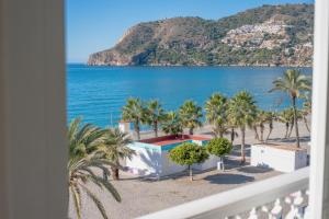 a view of a beach with palm trees and the ocean at Apartamento LH Beach frente al mar in La Herradura