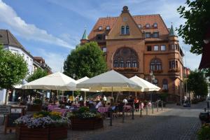 mensen aan tafels onder parasols voor een gebouw bij Homefeld Suite - Elegante und moderne Ferienwohnung zentral in Hünfeld bei Fulda mit Küche, kostenlosem Parkplatz und WLAN in Hünfeld
