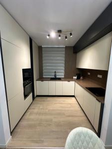 une grande cuisine avec des placards blancs et un évier dans l'établissement Pipera Luxury Suite - Victoria Homes, à Voluntari