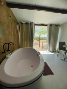 a large white tub in a room with a window at Suítes Domo do Matto in Garanhuns
