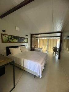 a bedroom with a large white bed and a table at Suítes Domo do Matto in Garanhuns