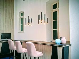 a reception counter with pink chairs and a desk at Vlachos Hotel in Delitzsch +15 photos