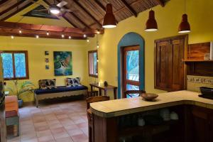 a kitchen with yellow walls and a living room with a couch at Casa Almendras - Magic Stay in Ometepe in Santa Cruz