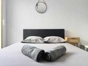 a bed with three rolled towels on it with a clock at Charmant T2 Oullins centre avec terrasse in Oullins
