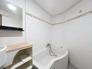 a white bathroom with a tub and a sink at Charmant T2 Oullins centre avec terrasse in Oullins +1 photo