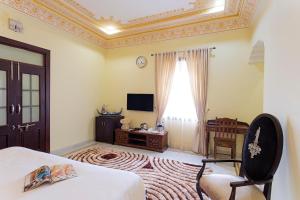 um quarto com uma cama, uma televisão e uma janela em Syna Heritage Hotel em Khajuraho