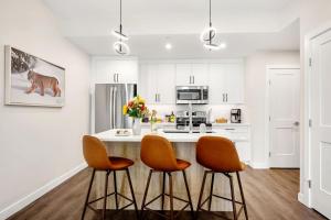 a white kitchen with orange chairs and a counter at New 2BR in DT Golden with AC, Balcony, BBQ, Sleeps 6 in Golden