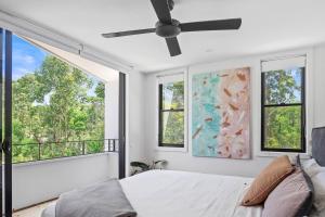 a bedroom with a bed and windows and a ceiling fan at Woodalla Way - Family Coastal Duplex Walk to Beach in Narrawallee