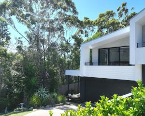 a house in the bush with trees in the background at Woodalla Way - Family Coastal Duplex Walk to Beach in Narrawallee