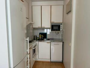 a small kitchen with white cabinets and a microwave at Convenient Apartment for 4 with Sauna in Törnävä