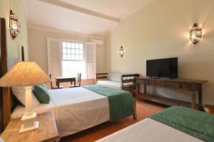 a bedroom with two beds and a flat screen tv at Quinta das Águas Hotel in Itapira