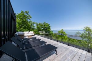 a row of benches sitting on a deck overlooking the water at Le Föss, Fleuve, Sauna & Spa in Petite-Rivière-Saint-François