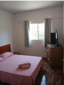 ein Schlafzimmer mit einem Bett, einem Fernseher und einem Fenster in der Unterkunft Casa túnel 2 in Pôrto de Pedras
