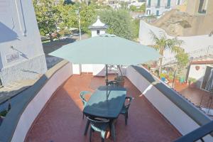 a table and chairs under an umbrella on a balcony at Al Primo Piano in Forio d'Ischia
