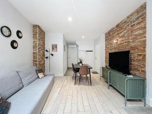 a living room with a couch and a brick wall at Appartement confortable Oullins centre in Oullins