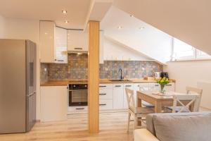 a kitchen with white cabinets and a table with chairs at The Lion Rooms -Apartamenty z aneksami kuchennymi in Ustroń