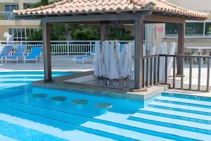a gazebo with white umbrellas next to a pool at Apart hotel a Beira Mar na praia do Recreio in Rio de Janeiro