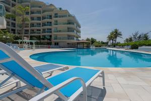 a swimming pool with a chair and a building at Apart hotel a Beira Mar na praia do Recreio in Rio de Janeiro