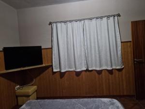a bedroom with a white curtain and a television at Quinta do silva in Celorico de Basto