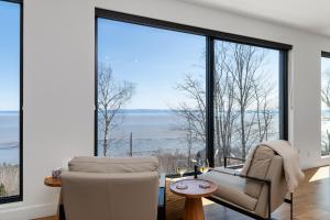 a living room with a view of the water at Le Föss, Fleuve, Sauna & Spa in Petite-Rivière-Saint-François