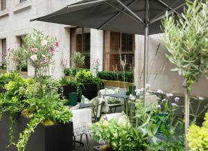 a patio with tables and chairs and potted plants at Hotel Cafe Royal in London