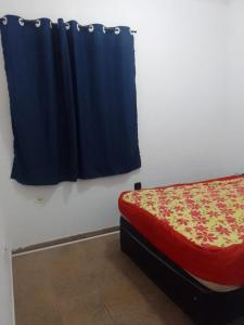 a bedroom with a bed and a blue curtain at Apto 2 dorm com elevador in São Vicente