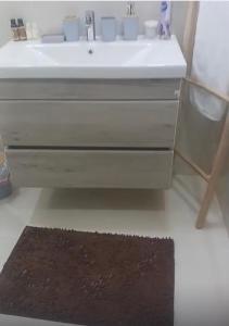 La salle de bains est pourvue d'un lavabo blanc et d'un tapis noir. dans l'établissement 3 room appartment branes, à Tanger