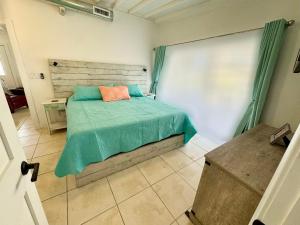 a bedroom with a bed with a green comforter at Waterfront Boat Lift Bungalow in St Pete Beach +54 photos