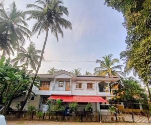 a house with palm trees in front of it at Roque's Place Goa in Betalbatim