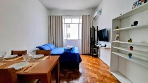 un salon avec une table et un canapé bleu dans l'établissement Sunrise Flamengo - 4 Hóspedes, Metrô e Privativo!, à Rio de Janeiro