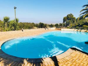 ein großer blauer Pool in einem Park in der Unterkunft Into the Sunset Manor in Gordonʼs Bay