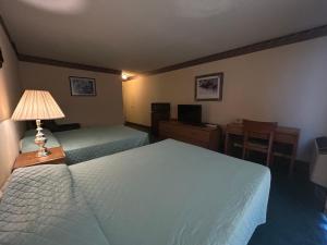 a hotel room with two beds and a table and a lamp at Candlelight Inn by Capital O Scottsbluff in Scottsbluff