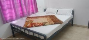Una cama en una habitación con una cortina rosa. en Honey Drops Homestay by Hebron, en Kanthalloor