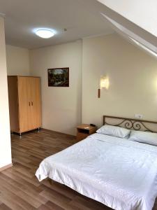 um quarto com uma cama branca e piso em madeira em Hotel Sofia em Orhei