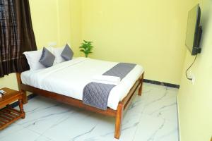 Schlafzimmer mit einem Bett mit weißer Bettwäsche und einem TV in der Unterkunft Sandy Toes -Ocean Balcony 2BHK & 2mins to Promenade in Puducherry