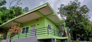ein grünes Haus mit einem Balkon und Bäumen in der Unterkunft The Town Cascade in Madikeri