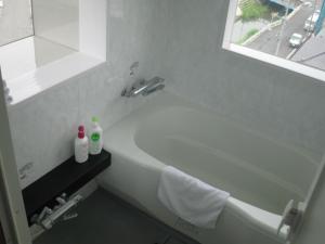 Baño blanco con bañera y lavamanos en Sakura Hotel Oami, en Ōami