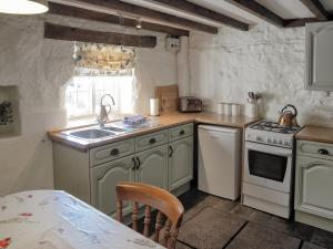 una cucina con un lavello, un fornello e un tavolo di Shire Cottage a Highpeak Junction